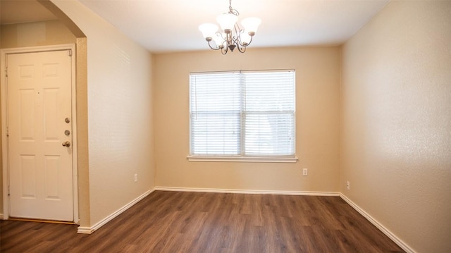 empty room featuring dark wood-type flooring and an inviting chandelier