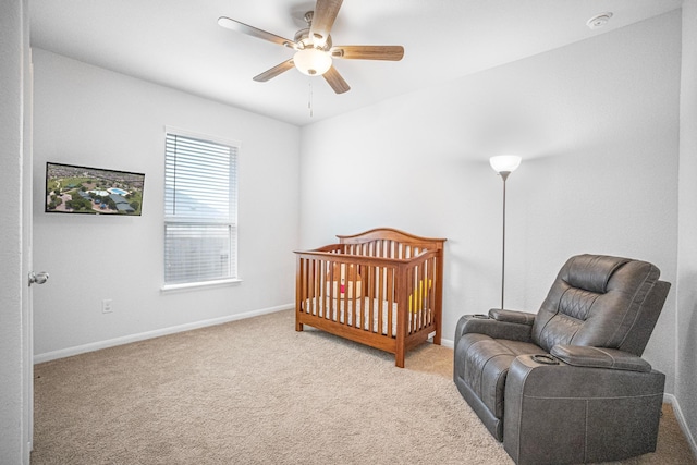 carpeted bedroom featuring ceiling fan and a crib