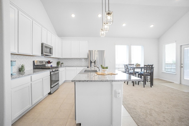 kitchen featuring stainless steel appliances, backsplash, lofted ceiling, white cabinets, and sink