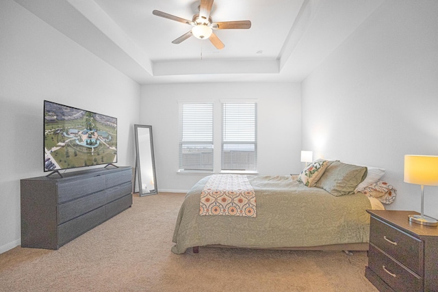 carpeted bedroom with ceiling fan and a raised ceiling