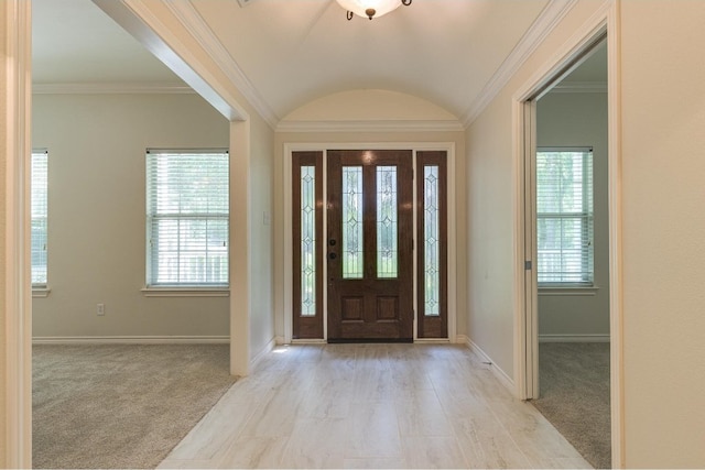 foyer entrance featuring vaulted ceiling, ornamental molding, and light carpet