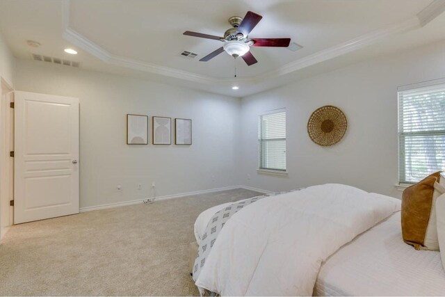 bedroom with ceiling fan, a raised ceiling, ornamental molding, and light carpet