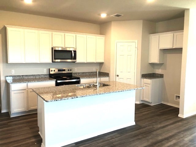 kitchen featuring white cabinetry, stainless steel appliances, and an island with sink