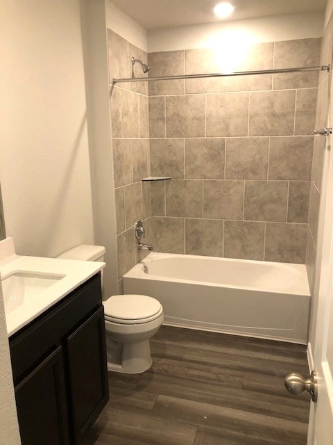 full bathroom featuring hardwood / wood-style flooring, toilet, vanity, and tiled shower / bath