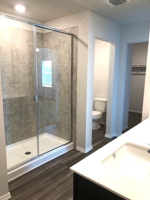 bathroom featuring hardwood / wood-style floors, vanity, an enclosed shower, and toilet