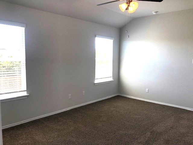 carpeted empty room with ceiling fan and lofted ceiling