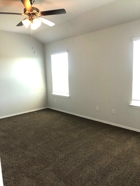 carpeted empty room with ceiling fan and lofted ceiling