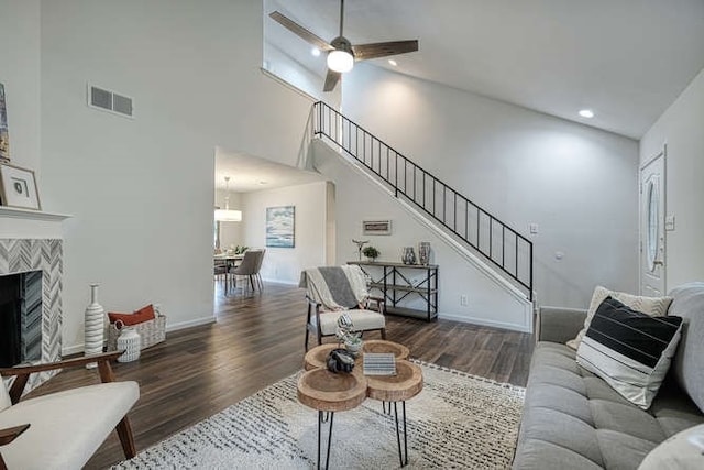 living room featuring high vaulted ceiling, ceiling fan, a tile fireplace, and dark hardwood / wood-style floors