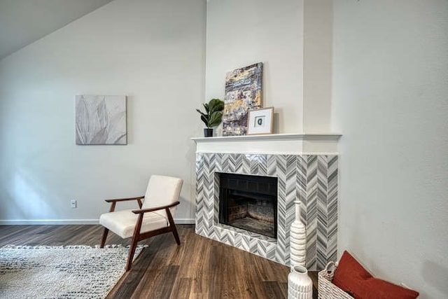 living area with dark hardwood / wood-style flooring, lofted ceiling, and a tile fireplace