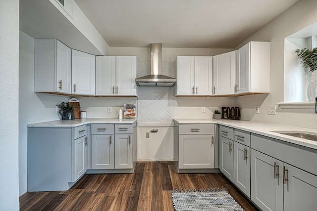 kitchen with white cabinets, wall chimney range hood, dark hardwood / wood-style floors, and gray cabinetry