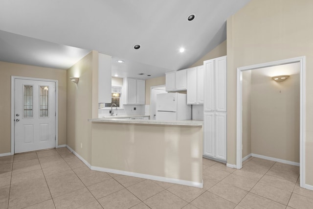 kitchen featuring white refrigerator, white cabinets, kitchen peninsula, light tile flooring, and vaulted ceiling