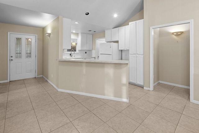 kitchen with kitchen peninsula, white cabinets, white fridge, and light tile floors