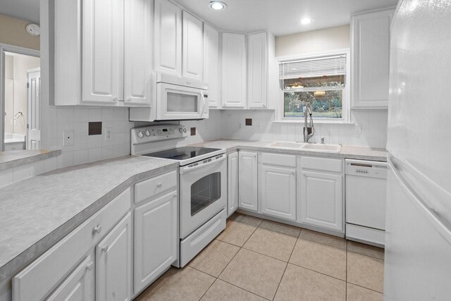 kitchen with white cabinetry, white appliances, sink, tasteful backsplash, and light tile floors