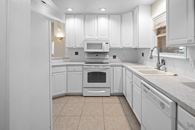 kitchen featuring white appliances, backsplash, light tile floors, sink, and white cabinets