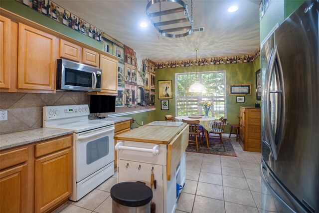 kitchen featuring appliances with stainless steel finishes, tasteful backsplash, light tile patterned floors, and a center island