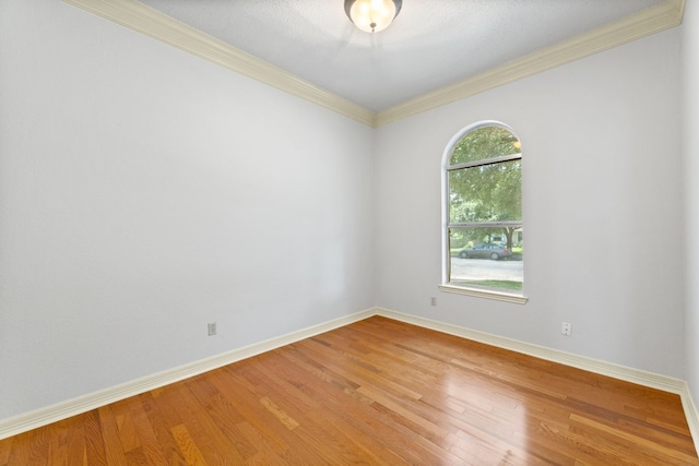 empty room with crown molding and wood-type flooring