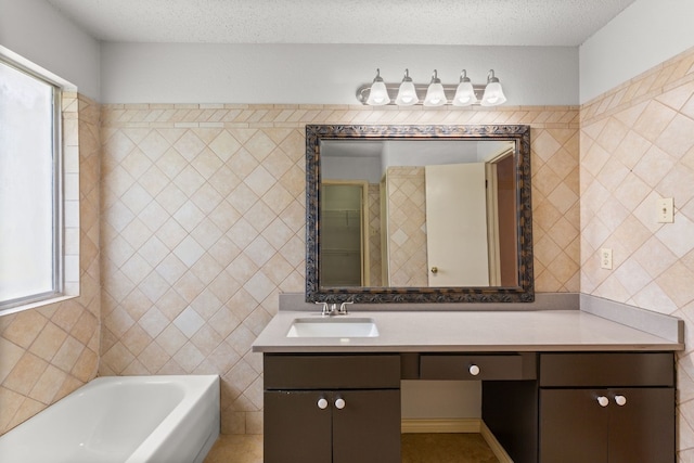 bathroom featuring a washtub, a textured ceiling, tile walls, and vanity