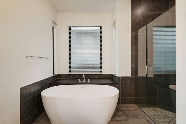 bathroom with a wainscoted wall, tile walls, and a stall shower