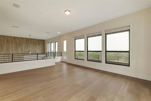 spare room with wooden walls, visible vents, baseboards, light wood-style flooring, and recessed lighting