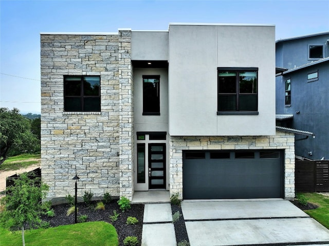 contemporary home with an attached garage, stone siding, driveway, and stucco siding