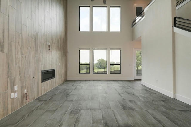 unfurnished living room featuring a high ceiling, a fireplace, and baseboards