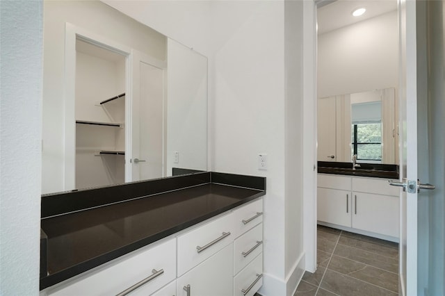 bathroom with tile patterned floors, recessed lighting, vanity, and a walk in closet