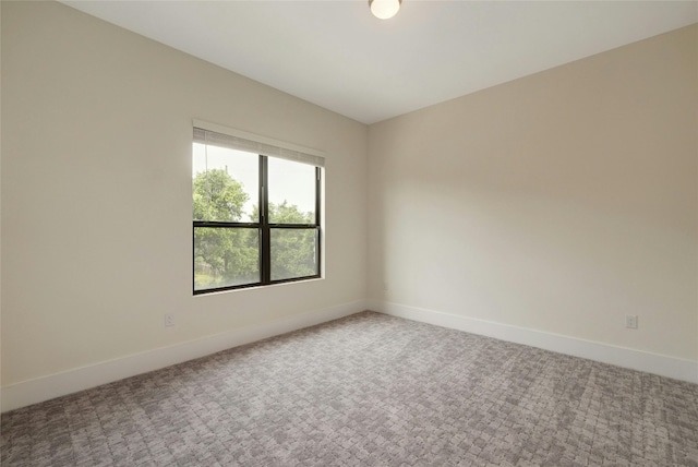 spare room with baseboards and carpet floors