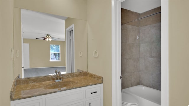 full bathroom featuring ceiling fan, vanity, tiled shower / bath combo, and toilet