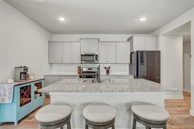 kitchen featuring tasteful backsplash, a center island with sink, stainless steel appliances, and sink