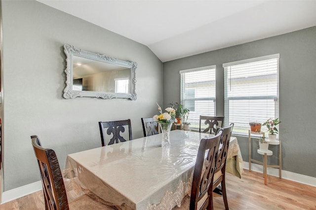 dining area with lofted ceiling, a wealth of natural light, and light hardwood / wood-style flooring