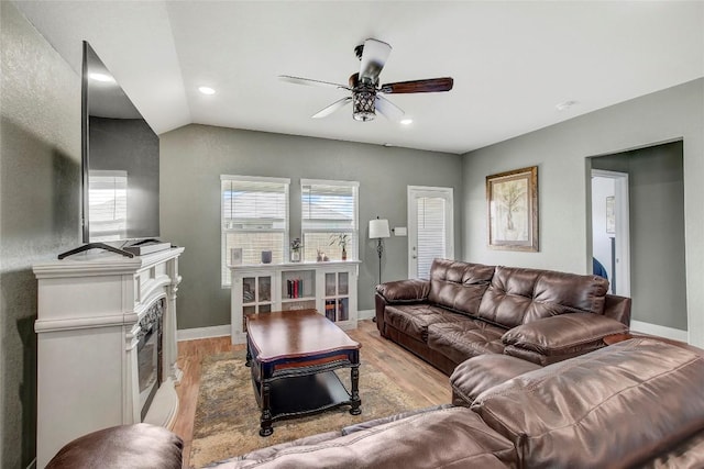 living room featuring ceiling fan, light hardwood / wood-style floors, and vaulted ceiling