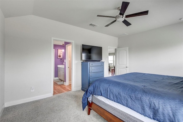 carpeted bedroom featuring ceiling fan, lofted ceiling, and ensuite bath