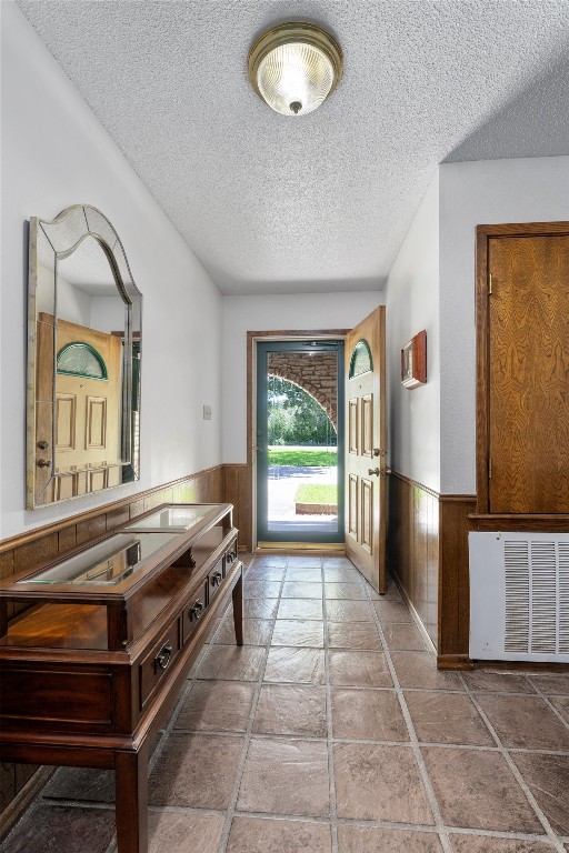 doorway featuring a textured ceiling and wooden walls