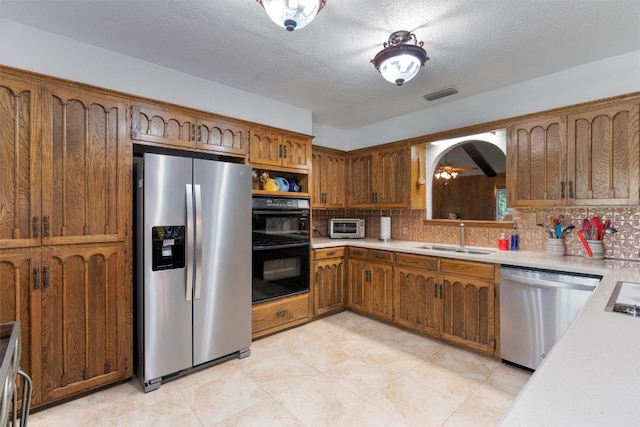 kitchen with appliances with stainless steel finishes, sink, backsplash, a textured ceiling, and ceiling fan