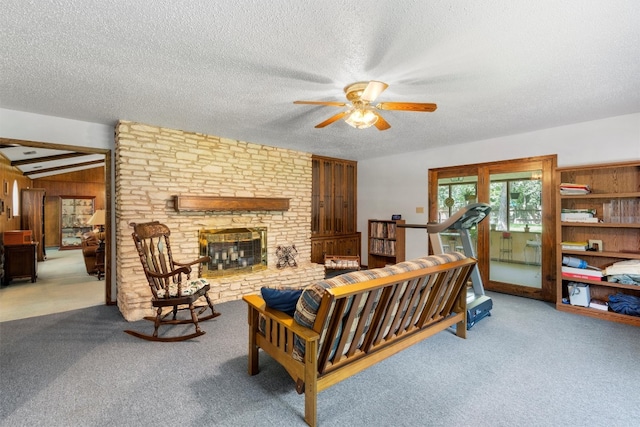 living room featuring ceiling fan, a textured ceiling, wood walls, carpet floors, and a fireplace