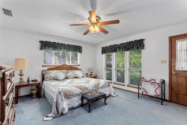 bedroom with ceiling fan, a textured ceiling, carpet, and multiple windows