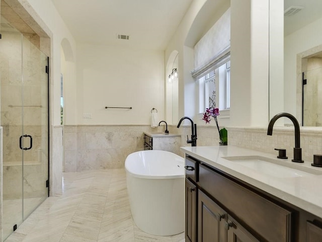 bathroom with vanity, shower with separate bathtub, and tile walls