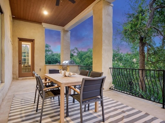 balcony at dusk featuring ceiling fan, a grill, exterior kitchen, and a patio area