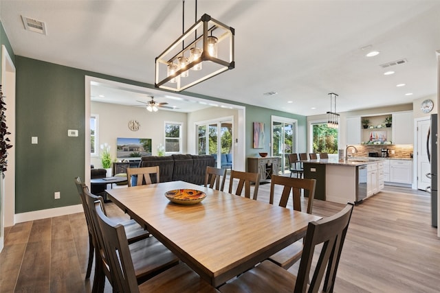 dining area with ceiling fan, light hardwood / wood-style floors, and sink