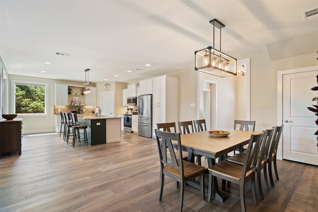 dining room featuring sink, light hardwood / wood-style flooring, and a chandelier