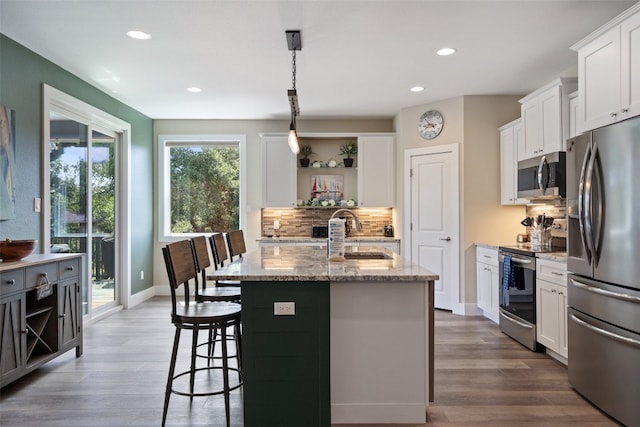 kitchen featuring light stone countertops, sink, hardwood / wood-style flooring, and appliances with stainless steel finishes