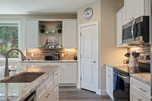 kitchen featuring tasteful backsplash, white cabinetry, dark wood-type flooring, appliances with stainless steel finishes, and sink