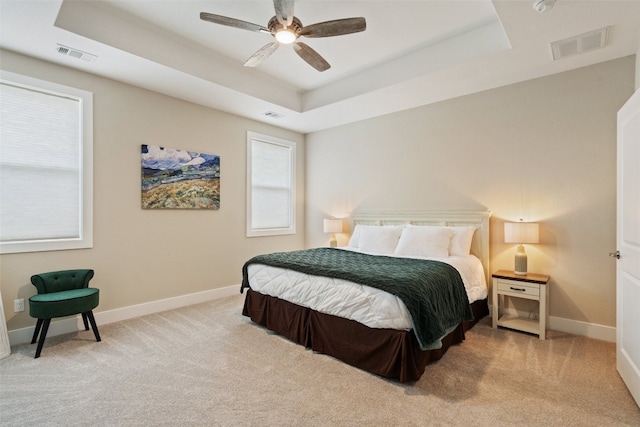 bedroom with a tray ceiling, carpet, and ceiling fan