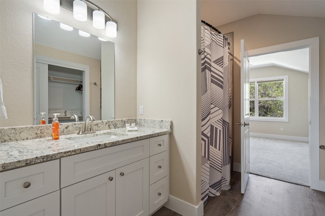 bathroom with vaulted ceiling, hardwood / wood-style floors, and vanity