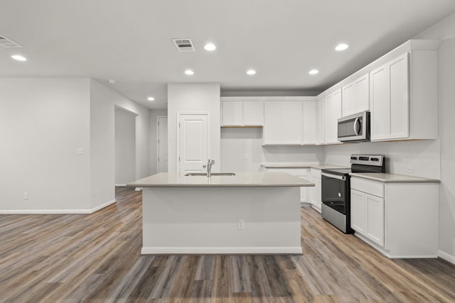 kitchen with sink, white cabinets, appliances with stainless steel finishes, and a kitchen island with sink