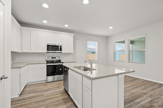 kitchen with sink, white cabinetry, appliances with stainless steel finishes, and a center island with sink