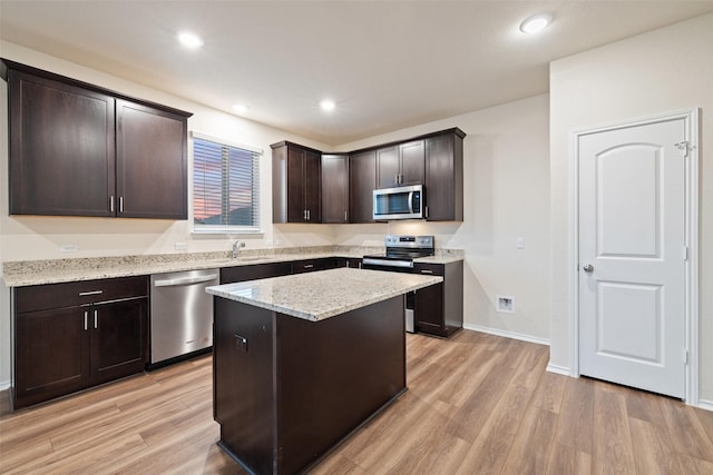 kitchen featuring dark brown cabinets, light wood-type flooring, appliances with stainless steel finishes, and a kitchen island