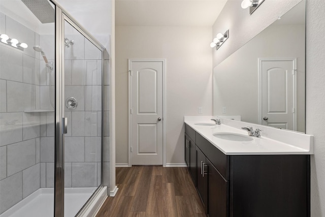 bathroom with hardwood / wood-style flooring, a shower with shower door, and vanity