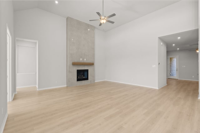 unfurnished living room with high vaulted ceiling, ceiling fan, a tile fireplace, and light hardwood / wood-style flooring