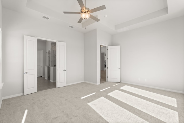 unfurnished bedroom featuring carpet, ceiling fan, and a raised ceiling